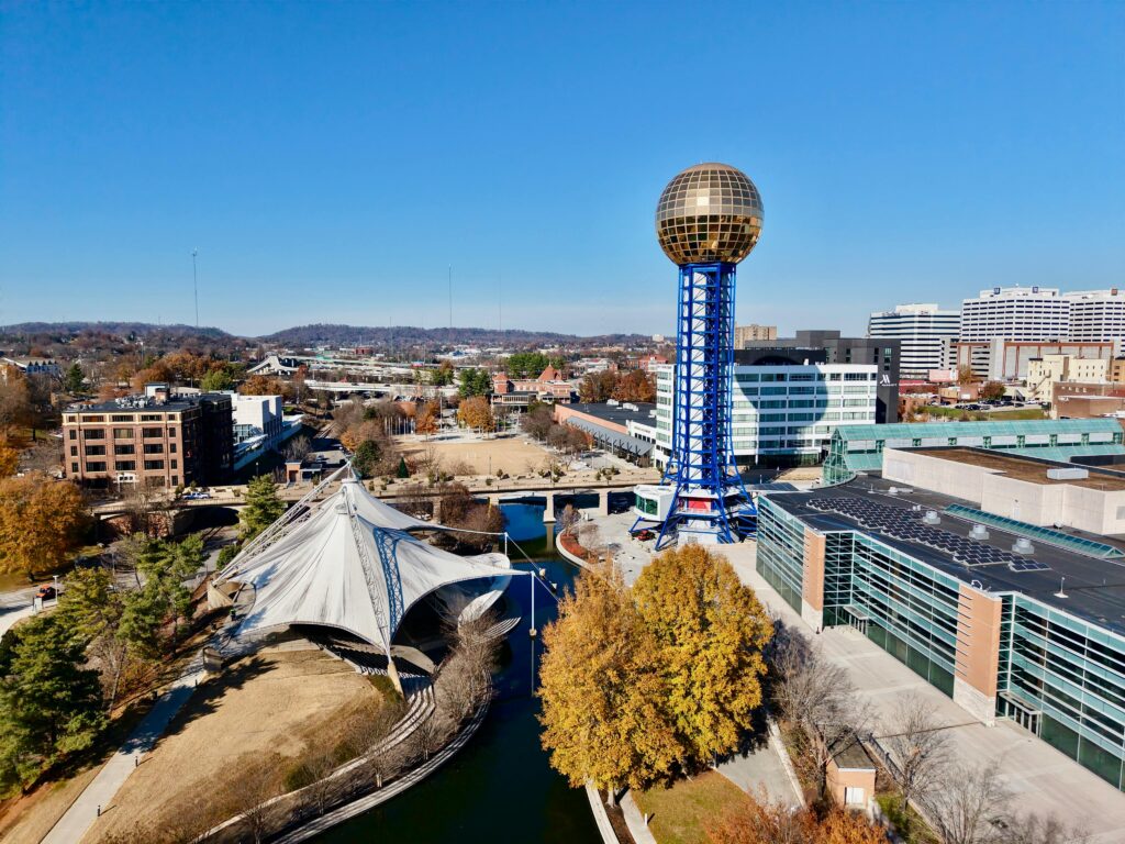 Drone view of the Sunsphere at World's Fair Park, Knoxville, showcasing modern architecture and fall foliage.